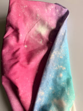 Load image into Gallery viewer, Close-up of a fabric item with an all-over galaxy-style print featuring a color-wash design in pink, purple, blue, and teal with white speckles resembling stars

