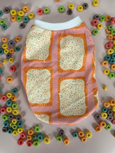 Load image into Gallery viewer, Close-up of a fabric item with an all-over novelty print featuring frosted toaster pastries with rainbow sprinkles and crimped orange edges, on a pink background
